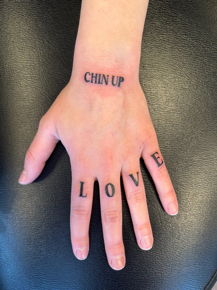 Fine line lettering tattoo across the fingers, Phantom Avenue Edmonton