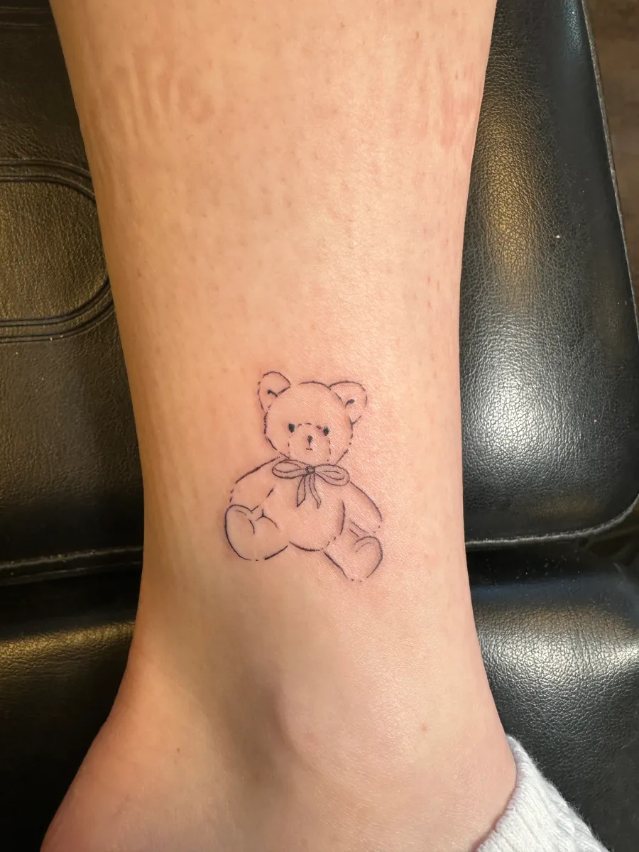 Fine line tattoo of a small figure on the lower leg, Phantom Avenue Edmonton